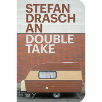 The book cover for An Double Take by Stefan Drasch. A vintage brown and cream caravan is parked in front of a building with a red brick lower half and a white panelled upper half. The author's name is printed in large, brown letters on the white section, while the title is printed in white letters on the brick section.
