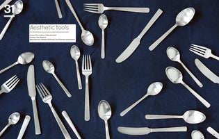 A flat-lay photograph of sleek, silver-colored cutlery, including various spoons, forks, and knives, scattered across a dark blue textured background. In the upper left corner, a white box with text reads Aesthetic tools and provides details about the Grand Prix cutlery by Kay Bojesen.