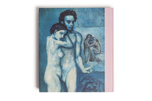 A front view of a hardcover book with a pink cloth spine against a white background. The cover features Pablo Picasso's painting, La Vie, from his Blue Period. The artwork depicts a somber, nearly nude man and woman embracing, rendered in various shades of blue.