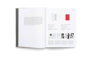 An overhead view of an open art book with a textured cover. The left page contains a large block of italicized German text. The right page has a catalog-style layout with descriptions, small black-and-white photographs, and two small color blocks at the top, one grey and one red.