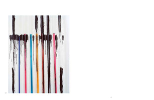 An abstract photograph shows several brightly colored, thin vertical rods against a white textured background. The rods, in shades of blue, pink, cyan, and orange, are partially obscured by thick, black paint that drips down from the top of the frame, creating a stark contrast.