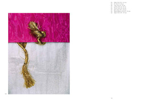 An abstract artwork on a white page, featuring a horizontal composition. The top half is a glossy, vibrant magenta fabric with a wavy texture. The bottom half is a textured, silvery-white surface. A thick, metallic gold rope with frayed ends is knotted on the magenta section and hangs down over the silver.