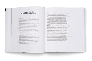 A high-angle photograph of an open book with white pages and black text, resting on a white surface. The book is open to a two-page spread, with the coil binding visible in the gutter. The left page features the title GRAND THEMES; OR, FIGURATIVE POLITICALITY in bold, capital letters.