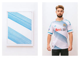 A split image comparing a minimalist art print to a football jersey. On the left, a framed picture on a white wall shows two diagonal bands of thin, light blue lines. On the right, a man with curly hair and a beard models a white Olympique de Marseille jersey featuring the identical graphic pattern across the chest.