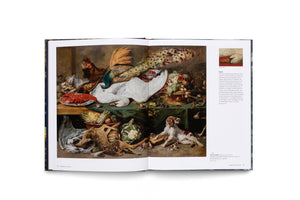 A photograph of an open art book. The left page displays a large, opulent still life painting of a feast, featuring a dead swan, a peacock, a lobster, a deer, and baskets of fruit and vegetables. The right page contains descriptive text and a small detail photo of a swan's head.