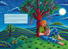 A vibrant, textured illustration shows a large, red-haired man with a beard holding a small Black child in his lap. They are sitting under a flowering tree on a rolling green and purple hill at night. The sky is dark blue with a full moon and stars. In the foreground, two small rabbits sit in the grass. A box with German text is on the left.
