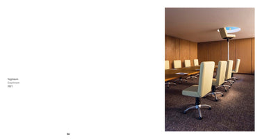 A book spread with the title Tagtraum, Daydream, 2021 on the left page. The right page displays a surreal image of a corporate conference room where one of the office chairs is elevated on a tall pole, extending through a circular hole in the ceiling to a bright blue sky with clouds.