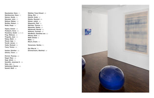 A two-page spread from an art catalog. The left page lists artists' names. The right page is a photograph of a minimalist art gallery with white walls and dark wood floors. In the foreground is a large, glossy, cobalt blue dome sculpture. A large abstract painting with horizontal blue washes hangs on a wall in the background.