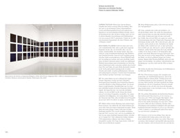 A two-page spread from an art publication, pages 150 and 151. The left page shows a photograph of Wolfgang Tillmans's 2006 installation, Memorial for the Victims of Organized Religions, which consists of a grid of 48 dark, square photographs arranged on two white gallery walls. Below the image and on the right page is an interview with the artist in German.