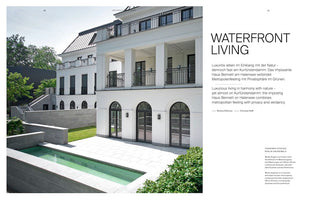 A two-page magazine spread titled WATERFRONT LIVING, featuring an exterior photograph of a luxurious, multi-story white villa with balconies and arched doors. The property includes a stone patio, a tiered garden with a manicured lawn, and a narrow rectangular swimming pool in the foreground. The text on the right describes the residence.