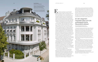 A two-page spread from an architecture book. On the left is a photograph of a large, elegant white building on a street corner. The multi-story building features a curved facade, numerous balconies, some with columns, and a dark grey roof with a circular rotunda. The right page contains descriptive text in both German and English.