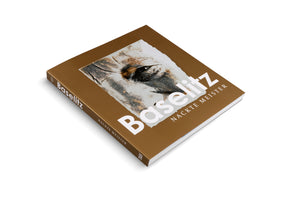 A three-quarter view of a hardcover book with a golden-brown cover, set against a white background. The cover features a close-up, textured image of an eye and the title Baselitz Nackte Meister in large white letters. The spine is also visible.