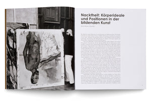 An open art book spread on a white surface. The left page shows a black and white photo of a man holding a large, abstract painting of a figure. The right page features the German title Nacktheit: Körperideale und Positionen in der bildenden Kunst, followed by several paragraphs of text.
