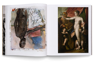 An open art book on a white surface, displaying two full-page paintings. On the left is a modern, expressionist painting of a winged Black man hanging upside down. On the right is a classical painting of a nude Venus with Mercury and two cherubs against a draped background.