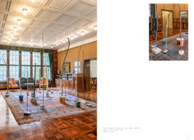 A two-page spread from an art publication. The left page shows an installation of numerous tall, thin sculptures made of curving metal and wood rods. The sculptures are individually set in simple bases like buckets and concrete blocks and are arranged on a large oriental rug inside a formal room with wood parquet floors, paneled walls, and a coffered ceiling. The right page features a smaller, detailed photo of the installation and text below it.