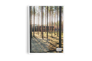 The back cover of a book with a large photograph of a modern, dark building with glass walls, seen through the tall, slender trunks of pine trees in a sunlit forest. Below the photo is a block of text and a barcode.