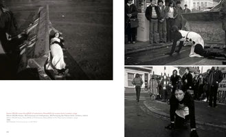 A book page displaying three black-and-white photographs of a performance art piece by ORLAN. The large photo on the left shows a woman in a white dress lying inside the metal bucket of an excavator. On the right, two photos show her crawling on all fours on a wet city street as pedestrians watch.