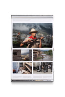 An open photobook, shot from above against a white background, displays a two-page spread with German text. The right page features a large color photo of two men in military-style uniforms holding rifles on a rooftop overlooking a city. Below, a grid of four smaller photos shows a cat falling by a skyscraper, a person carrying another across a river, a brutalist architectural plaza, and the legs of riot police standing over a person on the ground.