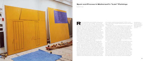 A two-page spread from an art book. The left page is a photograph of Robert Motherwell's studio, showing large, abstract yellow canvases leaning against a wall, one with a prominent purple rectangle. In the foreground are a blue tarp and a rolling cart with paint cans. The right page contains an essay titled Spain and Process in Motherwell's Late Paintings.