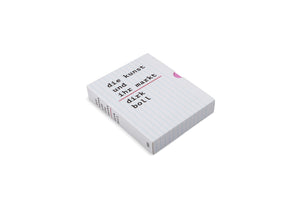A white book designed to look like a ruled notebook page lies on a white background. The title, die kunst und ihr markt, and the author, dirk boll, are printed in black typewriter font, separated by a red line. A pink tab sticks out from the top of the book.