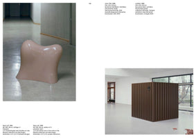 A two-page spread from an art catalog, page 144. On the left, a glossy, pink, biomorphic sculpture sits on a gray floor in a gallery hallway. On the right, a large, dark brown, slatted cubic sculpture stands in a white room with windows. Each artwork is accompanied by descriptive text in German and English.