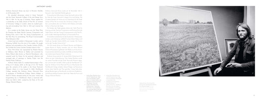A two-page book spread about artist Anthony Amies. The left page contains his biography in English and German. The right page features a black-and-white photograph of Amies, a man with long hair and a beard, sitting in a studio next to a large, detailed landscape painting on an easel.