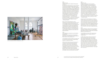 A two-page spread from a book with German and English text. The left page features a photograph of a spacious, white-walled artist studio in Berlin, 2000. A person on a ladder works on a large, colorful painting with a geometric pattern. A long table in the foreground is covered with dozens of paint cans and supplies.