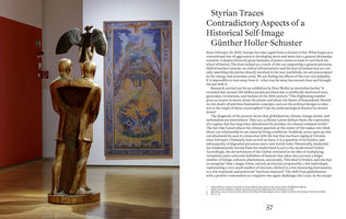 A two-page spread from a book or catalogue. The left page shows a photograph of a golden sculpture of two conjoined figures with a dark eagle on their shoulders, displayed in a gallery next to a large, colorful painting of a landscape. The right page features an article titled Styrian Traces Contradictory Aspects of a Historical Self-Image by Günther Holler-Schuster.