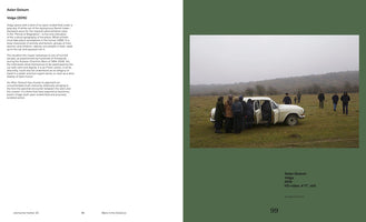 A still from Aslan Goisum's video Volga, presented as a book spread. The image on the right shows a large group of people in dark coats gathering in a wide, grassy field under an overcast sky. They are crowding around a small, vintage white car with its doors open, while others walk towards it from the background against a backdrop of misty hills. The left page contains descriptive text.