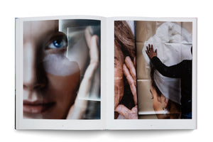 An overhead photograph of an open art book on a white surface. The left page shows a soft-focus, close-up portrait of a woman's face with a blue eye, overlaid with a shadowy silhouette. The right page displays a photographic collage of fragmented portraits, including an older person's hand and another person touching a creased image.