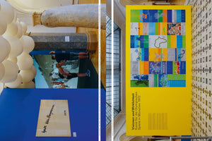 An overhead, composite photograph of a museum exhibition. The left side shows a blue wall with a handwritten note, a large photo of people outdoors, a sculpture of white spheres, and stone columns. The right side features a large yellow banner for the 1972 Munich Olympics, displaying a colorful grid of poster art in a hall with a patterned tile floor.