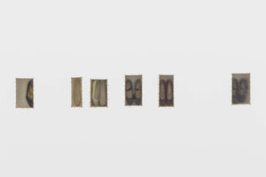 A horizontal series of six small, rectangular fabric patches with frayed edges is displayed on a white background. Each patch contains a faded, ghostly image of shoes. The images progress from close-ups of a single shoe to full pairs of ballet flats, varying in color and clarity, with the final image on the right being a dark, smudged abstract form.