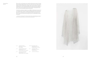 An open art book spread. The left page contains text under the title Disremembered 2013-21. The right page features a full-page photograph of a delicate, translucent, white textile piece hanging like a tunic against a plain white wall.