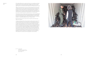 A two-page spread from a book. The left page contains text. The right page features a large photograph of two people, a man in a green uniform and a woman with curly hair, standing on top of a massive pile of decommissioned rifles inside a shipping container. The man is bent over, inspecting one of the guns.