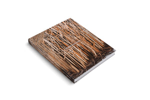 A hardcover art book for Doris Salcedo, shown at an angle on a white surface. The cover features a textured, close-up image of tangled, straw-like reeds in shades of brown and tan. The title is printed in white on the cover and the spine.