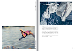 An open book showing a two-page spread. On the left page, a motion-blurred photo captures a person in a pink swimsuit diving into water. The right page features a photo of two white pelicans by dark blue water, with one arching its neck to preen its feathers. Both pages include blocks of German text.