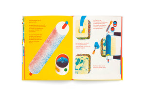 An open children's book with vibrant, stylized illustrations and German text, explaining the process of lithography. The left page has a bright yellow background with a large paint roller covered in red and blue speckles. The right page shows illustrated hands using a sponge and roller to apply ink to a printing stone.