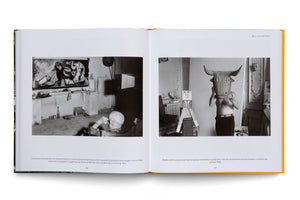 An open book with a yellow cover displays a two-page spread titled BULLFIGHTERS. On the left is a black and white photo of Pablo Picasso from behind, watching his bullfighting art in a studio. The right page shows a black and white photo of a shirtless Picasso wearing a large wicker bull mask.