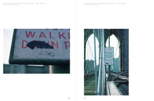 A two-page spread displays two photographs from the Brooklyn Bridge in 1977. The left image is a close-up of a weathered white sign with red lettering that says WALK, with a word below it partially obscured by a black patch. The right image shows a sign for bicycle riders on the bridge's walkway, with its iconic suspension cables and a stone archway visible in the background.
