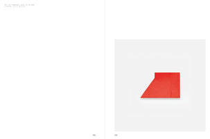 A two-page spread from a book. The left page contains text in the top corner. The right page shows a photograph of a minimalist artwork: a small, geometric shape painted a solid, vibrant red. The shape, an irregular quadrilateral, is centered against a plain white background.