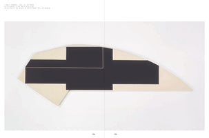 A photograph from a book showing an abstract painting from 1980, titled C-DGR-7 (DODGER). The artwork is on a long, irregularly shaped canvas and features a large, black, blocky cross-like shape against a cream-colored background. The painting is mounted on a white wall and the image is split vertically by the book's gutter.
