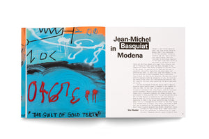 An open book spread about artist Jean-Michel Basquiat. The left page displays a vibrant, abstract painting with a bright blue background, featuring graffiti-style markings in black, white, and red. At the bottom of the painting is the text THE GUILT OF GOLD TEETH. The right page features the title of an essay, Jean-Michel Basquiat in Modena.