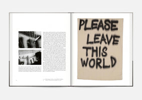An open art book laid flat. The left page contains dense text and two small black and white photographs. The right page displays a full-page artwork of a beige textile banner with the words PLEASE LEAVE THIS WORLD written in large, black, spray-painted style capital letters.