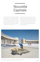 A magazine page with the French headline Nouvelle Capitale. The main photo shows construction workers on a large, paved plaza in front of a monumental, neo-classical building with a large colonnade. In the foreground, a worker in a blue shirt mixes cement with a shovel.