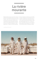 A full-page magazine spread titled La rivière mourante. The main photo shows three beekeepers in white protective suits and veiled helmets standing in a dry, dusty landscape. They are surrounded by white beehive boxes and a large swarm of bees fills the air around them.