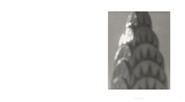 A soft-focus, black and white photograph on the right side of a page. The image is an artistic, blurry close-up of the Art Deco crown of the Chrysler Building, with sunlight creating glittering highlights. Below the image, the caption reads: Chrysler Building, 1997.