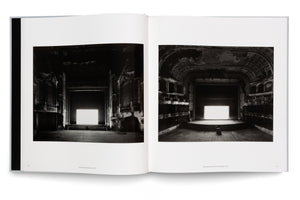 An open book is laid flat, displaying a two-page spread with black-and-white photographs of two different dilapidated, grand theaters. In each dark, crumbling auditorium, a large, brightly glowing white screen sits on the stage, creating a stark contrast with the surrounding decay.