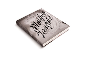 A hardcover book with a grey cover lies diagonally on a white background. The cover features a black-and-white photographic image overlaid with the title, Mother Tongues, in a large, elegant black script. Above the title, smaller text reads THE WORKS OF CAMILLE HENROT.