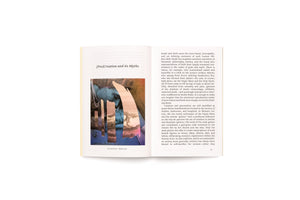 An open book on a white surface shows a two-page spread. The left page is titled (Pro)Creation and its Myths, with a collage artwork below. The artwork has a blue figure overlaid with vertical strips of textured paper in pink and brown. The caption reads Dos and Don'ts – My Bio, 2021. The right page features printed text discussing creation and birth, with the page number 19 at the bottom.