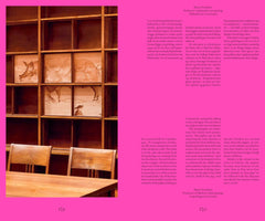 A two-page spread from a book. The left page shows a photo of a wooden shelving unit containing panels with anatomical drawings of a pig. In the foreground, there is a wooden table and two chairs. The right side features a bright pink column with text in Danish and English about medical research using piglets as substitutes for premature infants.